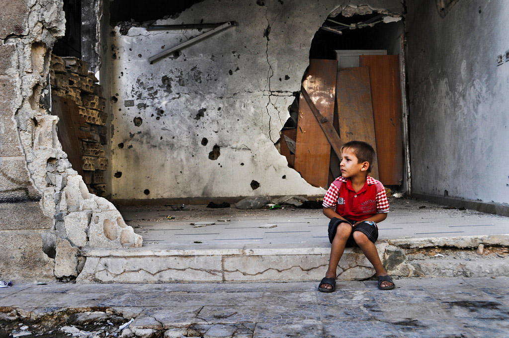 A young boy sits in front of a destroyed building in Homs, Syria. Photo: WFP/Abeer Etefa