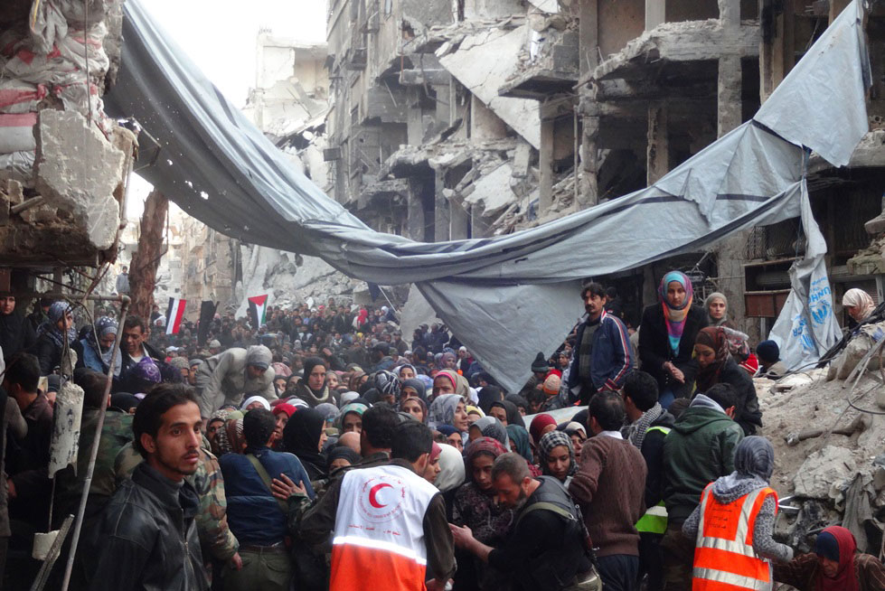A crowd awaits relief aid at the Yarmouk Palestinian refugee camp in the Syrian capital of Damascus in 2014. Photo: UNRWA