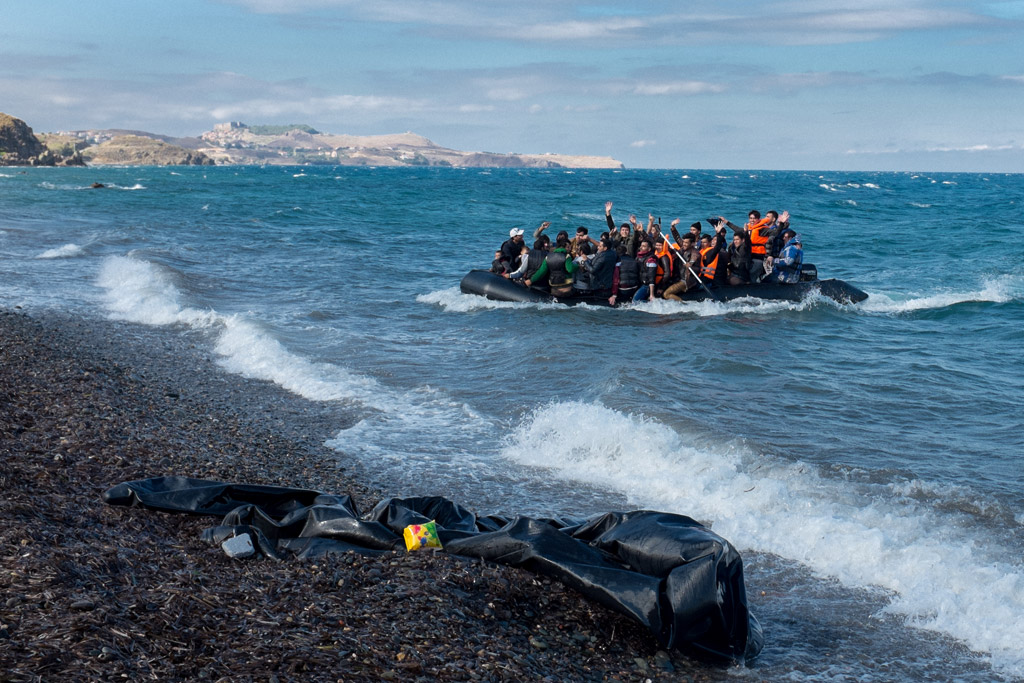 Newly-arriving refugees wave as the large inflatable boat they are in approaches the shore, near the village of Skala Eressos, on the island of Lesbos, in the North Aegean region of Greece. Photo: UNICEF/Ashley Gilbertson VII
