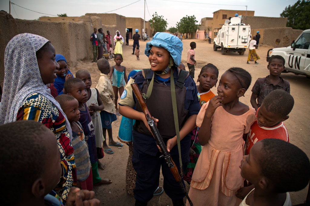 A UN peacekeeper from the UN Multidimensional Integrated Stabilization Mission in Mali (MINUSMA) Formed Police Unit (FPU) speaks to residents while patrolling the streets of Gao, in northern Mali. UN Photo/Marco Dormino