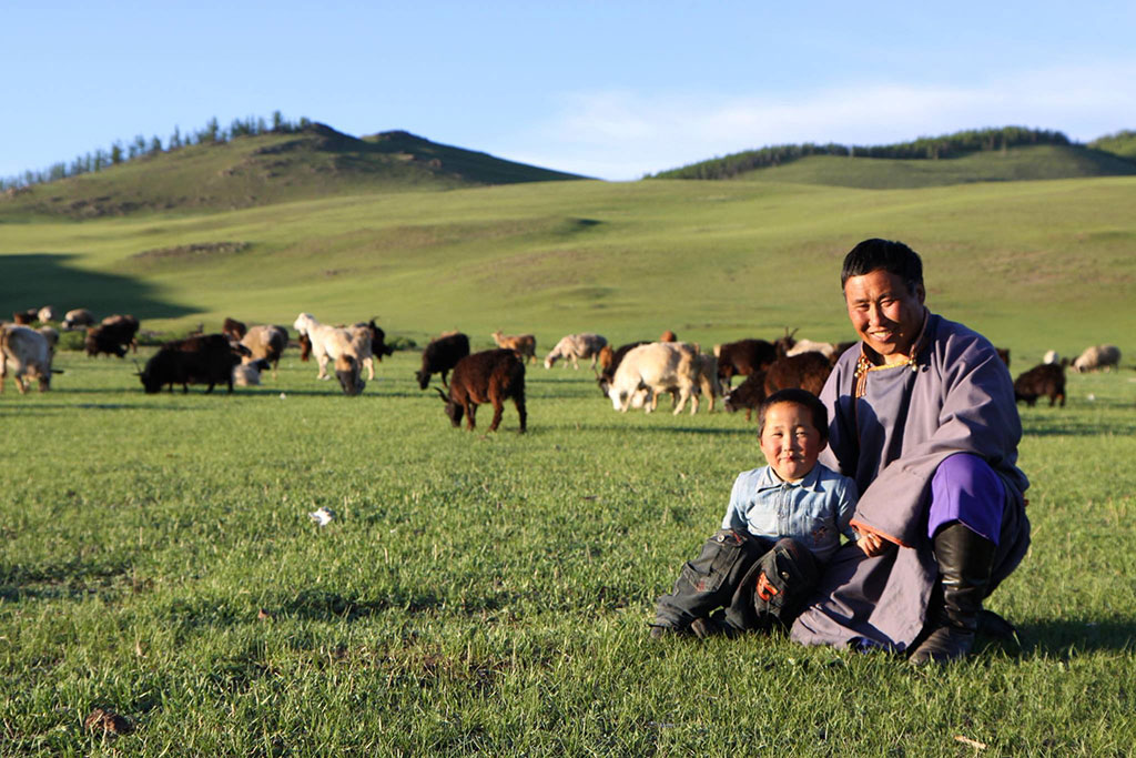 Altanshagai, with his son and herd in Mongolia. Altanshagai is the head of a herders group in Motont Soum that collectively cultivates 20 hectares of hay, protecting and preserving a nearby forest. They also collect pine nuts and wild berries to increase their incomes. Photo: IFAD/Susan Beccio