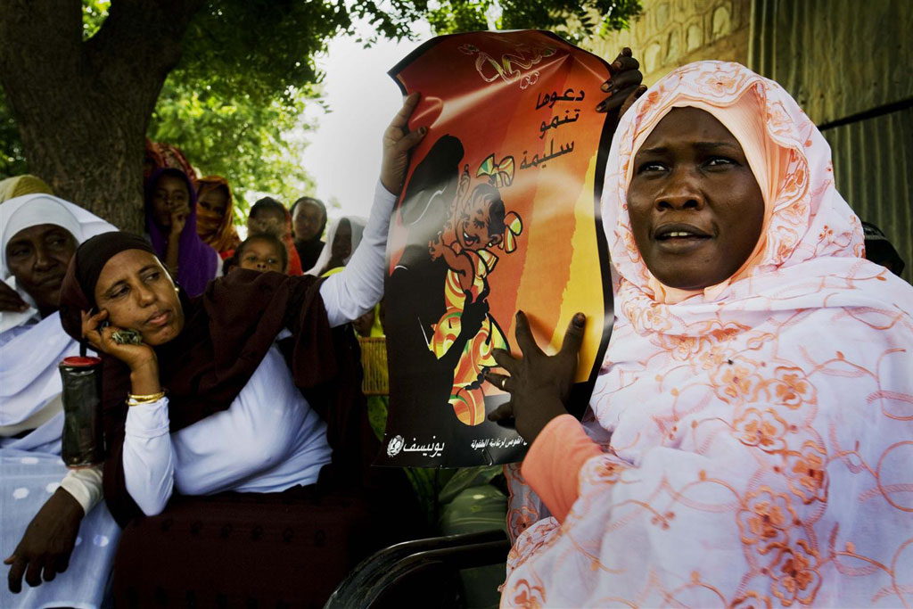 A woman in Sudan holds a poster promoting the collective abandonment of female genital mutilation. Photo:  UNICEF/UNI73778/Holt