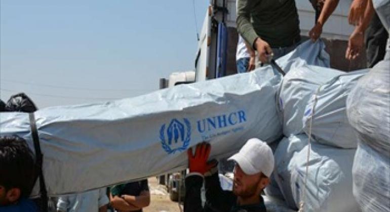 Workers unload trucks laden with hundreds of tents for families displaced by recent fighting in Iraq .© UNHCR/E.Colt