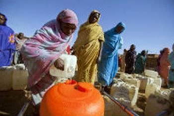 Women filling an orange Water Roller at a water distribution point in Sudan.