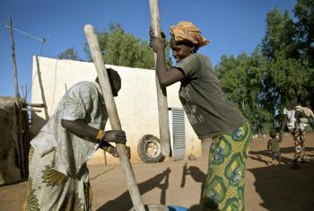 Two women grind rice outside a water pump station in the area of Koroyomme, Timbuktu.