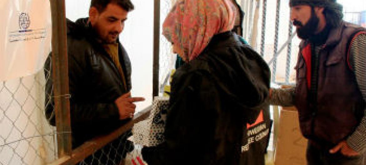 Homem sírio recebe doação de sapatos a seus filhos. Foto: OIM