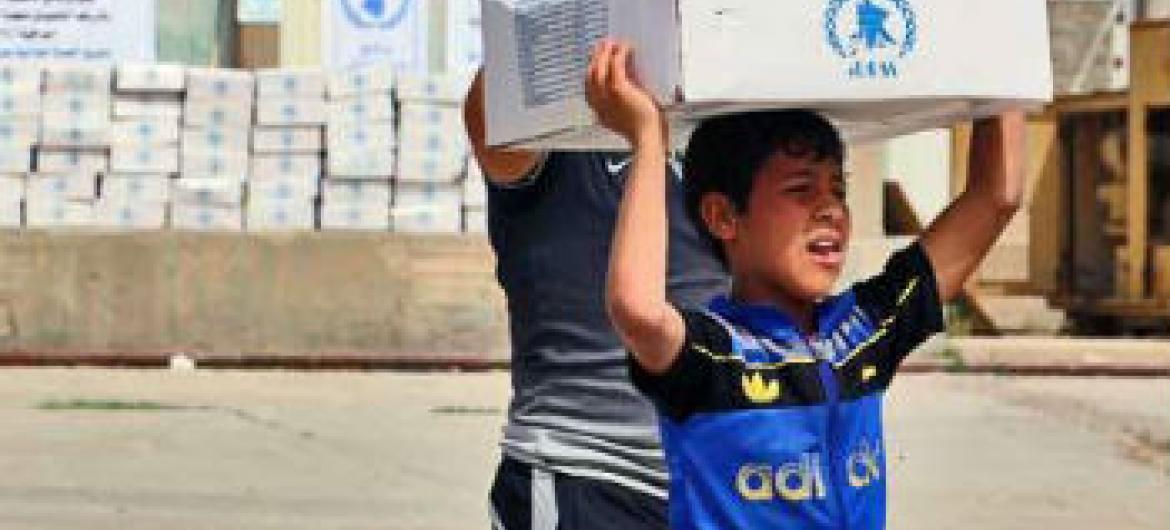 Menino iraquiano pega pacote com comida fornecido pelo PMA. Foto: PMA//Mohammed Al Bahbahani