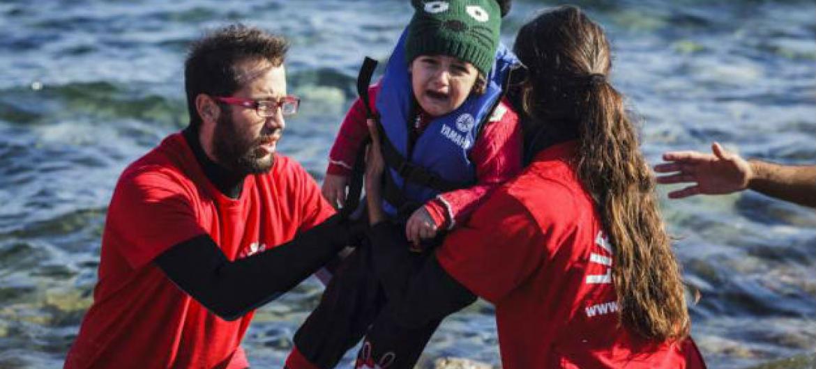 Voluntários ajudam criança a sair do barco em Lesbos, Grécia. Foto: Acnur/Achilleas Zavallis