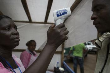 Na Serra Leoa, mulher mede temperatura de civil. Foto: © UNICEF/Bindra