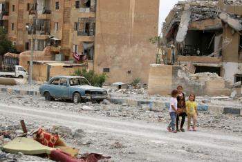 Crianças sírias passeiam no meio da destruição de prédios. Foto: Unicef/Souleiman