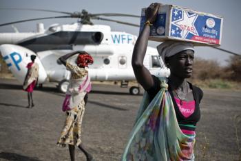 Mulher carrega kit de emergência alimentar entregue por um helicóptero do Programa Mundial de Alimentos no Sudão do Sul. Foto: Unicef/Holt